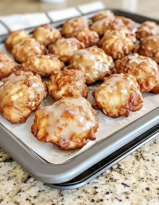 Baked apple fritters dusted with powdered sugar on a plate