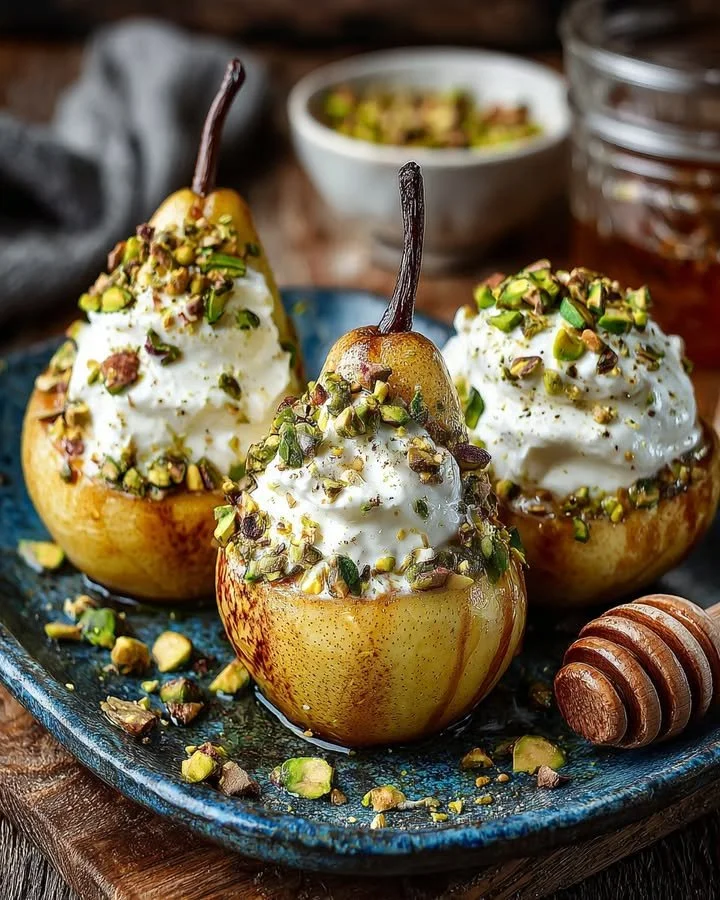Baked pears topped with whipped feta, pistachios, and honey on a plate.