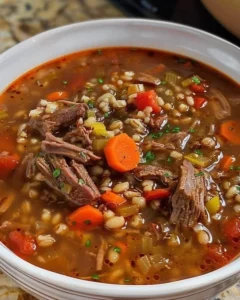 Bowl of hearty beef barley soup with vegetables and herbs