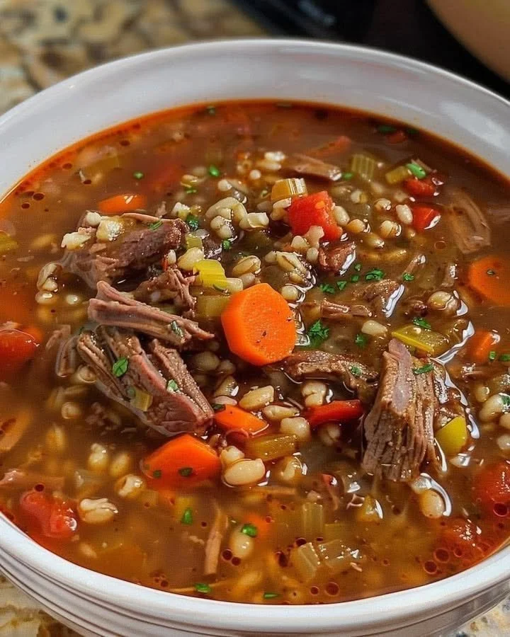 Bowl of hearty beef barley soup with vegetables and herbs