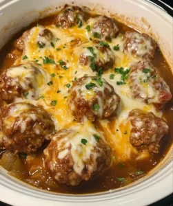 Plate of cheesy smothered meatballs topped with melted cheese and herbs