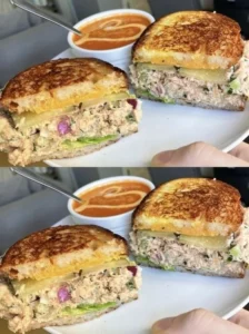 Delicious and fresh tuna sandwich with ingredients on a wooden table.