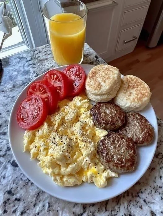 Sausage and egg breakfast served with biscuits and ripe tomatoes
