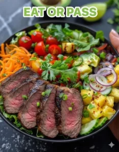 Colorful steak salad with tropical ingredients, garnished for a delicious meal.