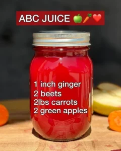 A glass of fresh ABC Juice surrounded by vibrant fruits and vegetables.