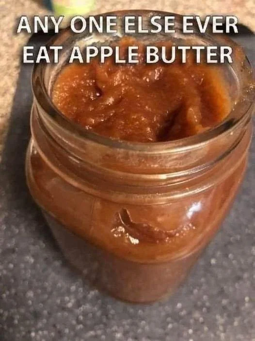 Jars of homemade apple butter spread on toast served with fresh apples