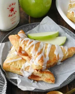 Homemade apple pie turnovers on a plate, dusted with powdered sugar