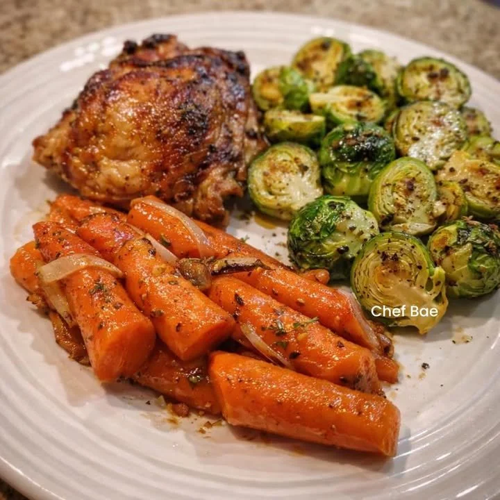 Baked chicken thighs with Brussels sprouts and glazed carrots on a plate