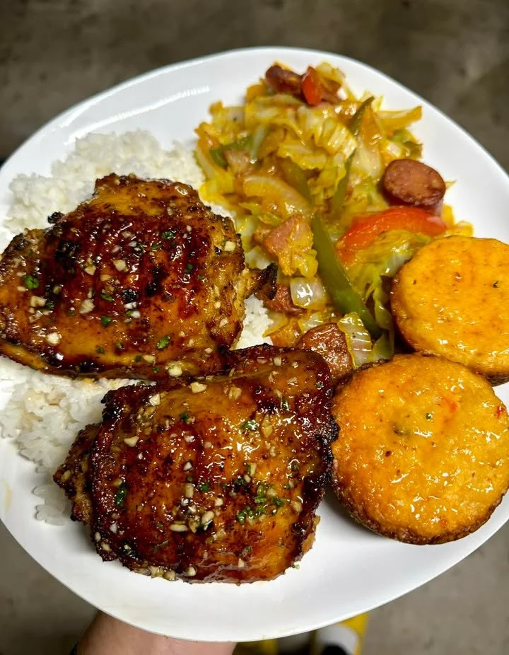 Baked chicken thighs served with rice and fried cabbage on a plate
