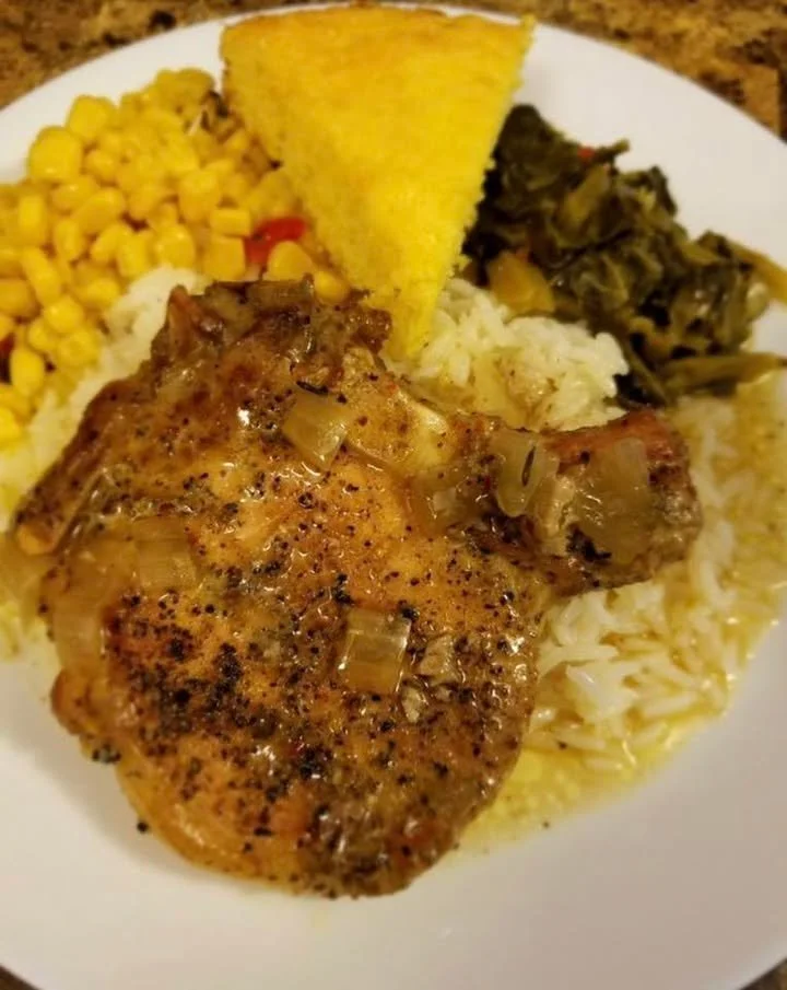 Baked pork chop dinner served with sides and garnished on a plate.