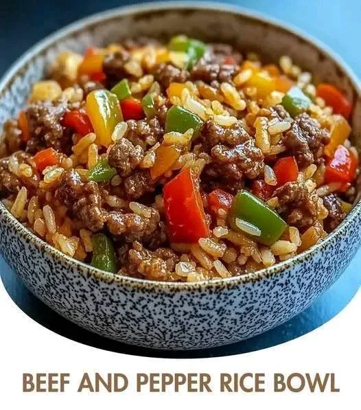 Beef and pepper rice bowl garnished with green onions on a wooden table