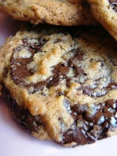 A plate of freshly baked chocolate chip cookies on a wooden table.