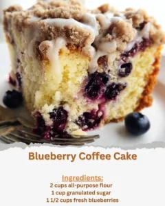 Slice of blueberry coffee cake on a plate with fresh blueberries