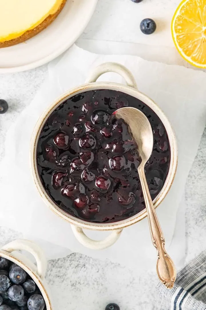Homemade blueberry compote served in a bowl with fresh blueberries on top.