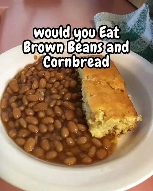 A delicious bowl of brown beans served alongside cornbread on a rustic table.