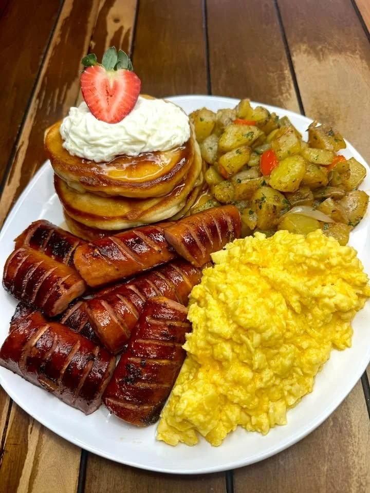 Colorful brunch plate with assorted dishes including eggs, bacon, and fresh veggies.