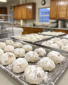 Plate of buttery pecan snowball cookies dusted with powdered sugar.
