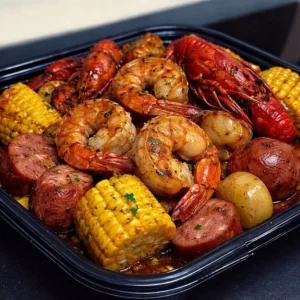 Cajun shrimp boil in garlic butter sauce served with vegetables and lemon