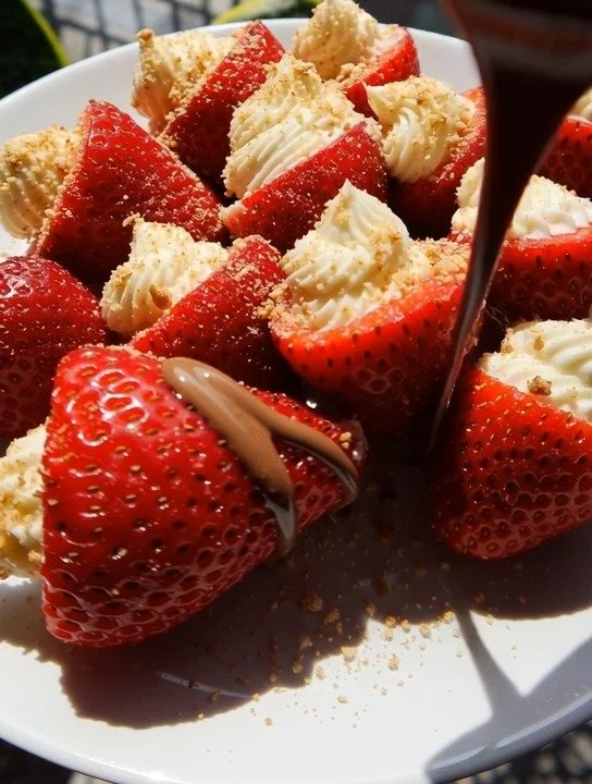 Cheesecake stuffed strawberries topped with creamy filling and a sprinkle of graham cracker.