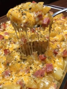 Cheesy ham potato casserole baked in a dish topped with cheese and herbs