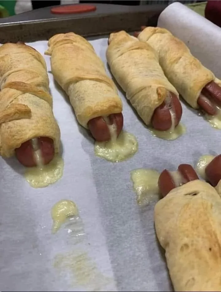 Cheesy pigs in a blanket served on a plate with dipping sauce.