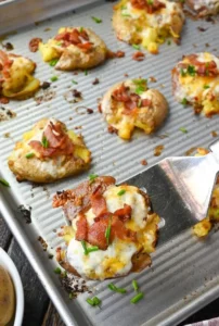 Cheesy smashed potato bites served on a plate with fresh herbs