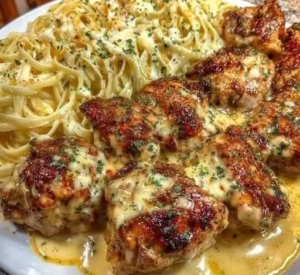 Plate of chicken bites with creamy Parmesan pasta garnished with herbs