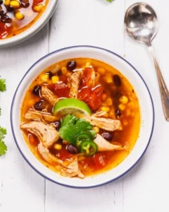 Bowl of homemade Chicken Tortilla Soup topped with crispy tortilla strips and avocado.