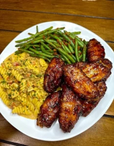 Delicious Chicken Wings served with Rotel Pasta and Green Beans on a plate.