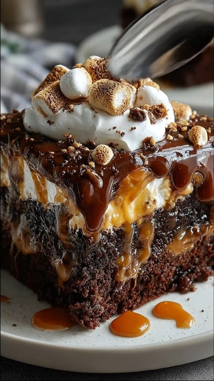 Chocolate Caramel Marshmallow Oozy Gooey Cake topped with marshmallows and caramel drizzle.