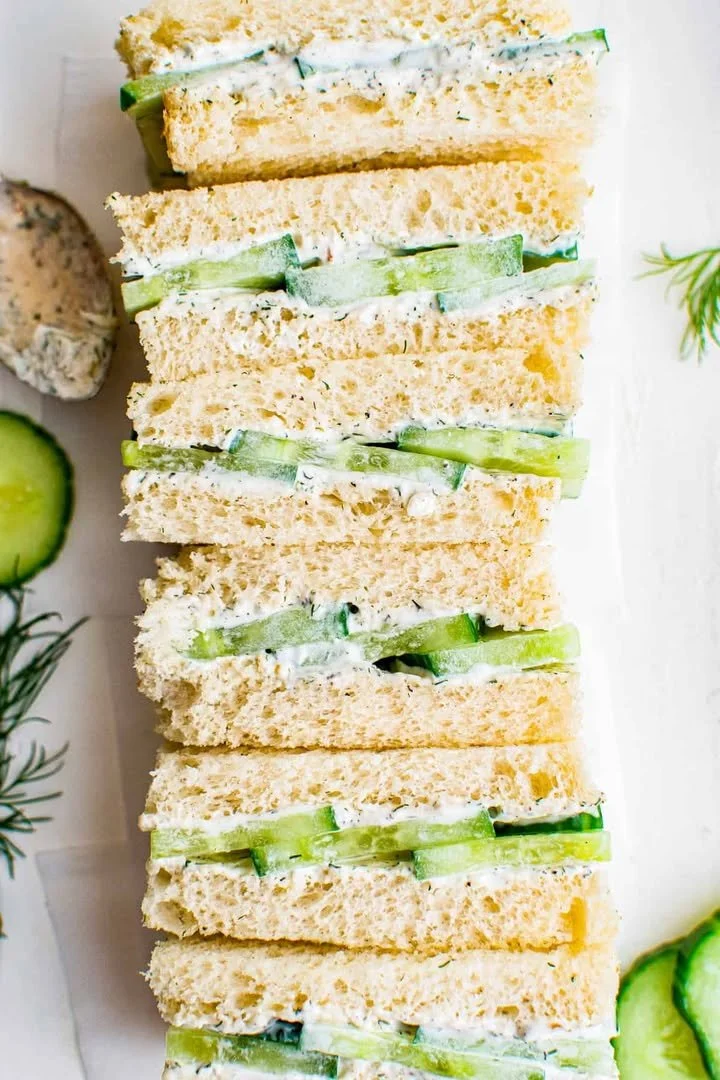 A plate of classic cucumber sandwiches with fresh herbs and cream cheese