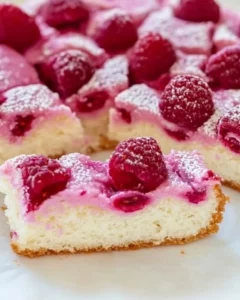 Slice of Coconut Raspberry Cake topped with fresh raspberries and coconut flakes