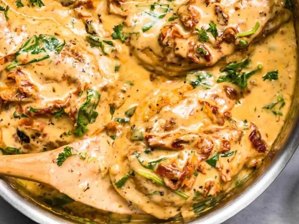 Creamy Tuscan chicken served on a plate with fresh herbs and vegetables