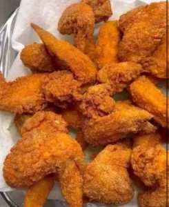 Plate of crispy fried chicken wings garnished with herbs