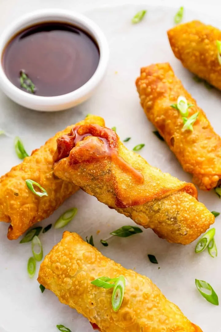 Crispy garlic ginger pork egg rolls served on a plate with dipping sauce