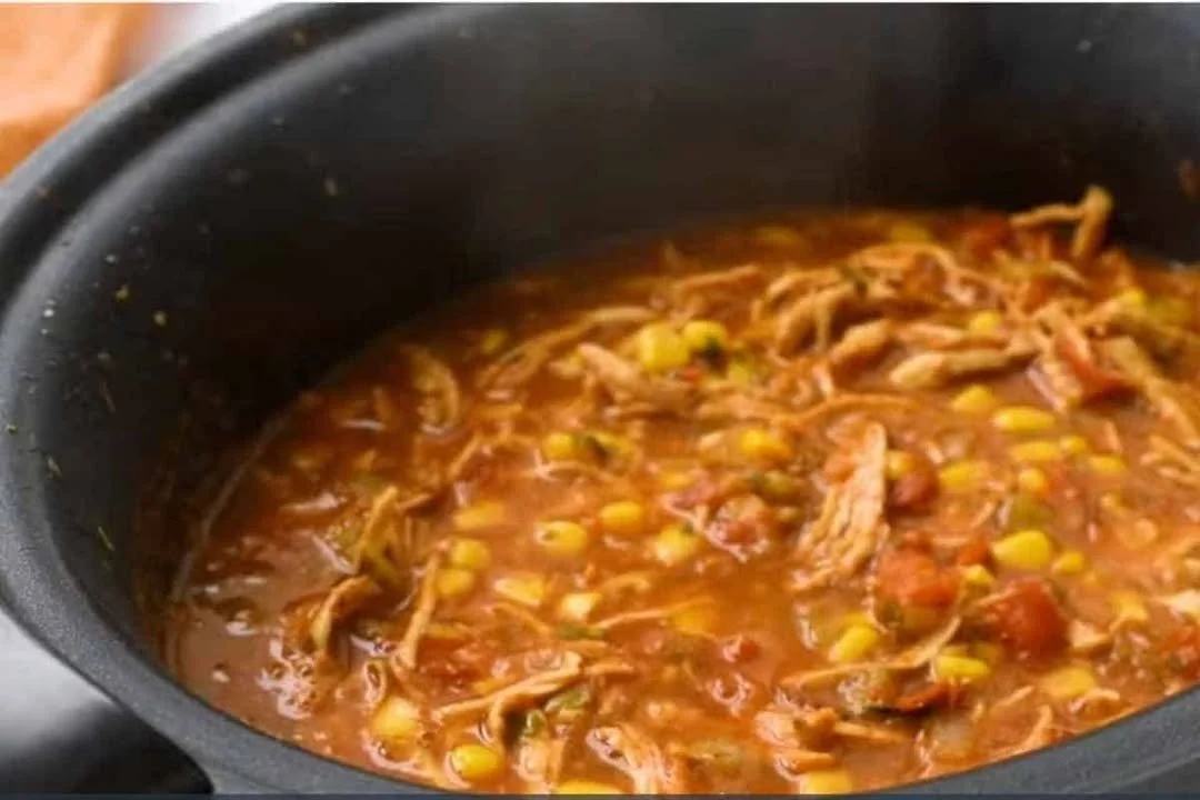 Bowl of delicious crock pot chicken tortilla soup garnished with tortilla strips.