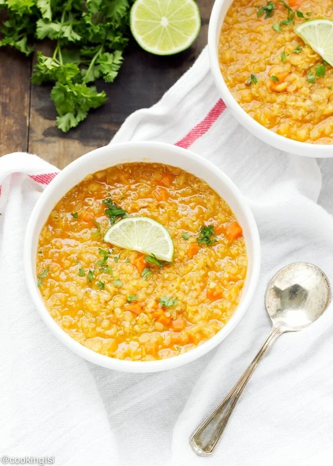 Bowl of curried lentil quinoa soup garnished with fresh herbs