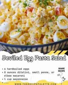 Bowl of deviled egg pasta salad with garnishes on a wooden table