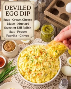 Bowl of easy deviled egg dip with crackers and vegetables for dipping
