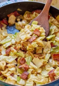 Fried cabbage with bacon, onion, and garlic in a skillet