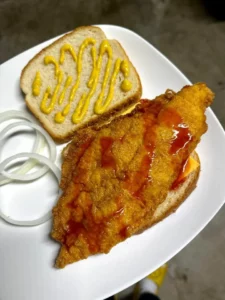Delicious fried catfish served on white bread with sides