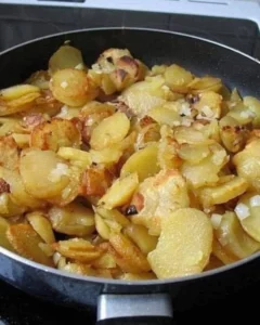 Fried potatoes and onions served with smoked sausage in a skillet.