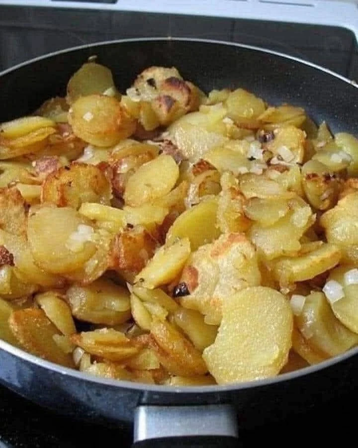 Fried potatoes and onions served with smoked sausage in a skillet.