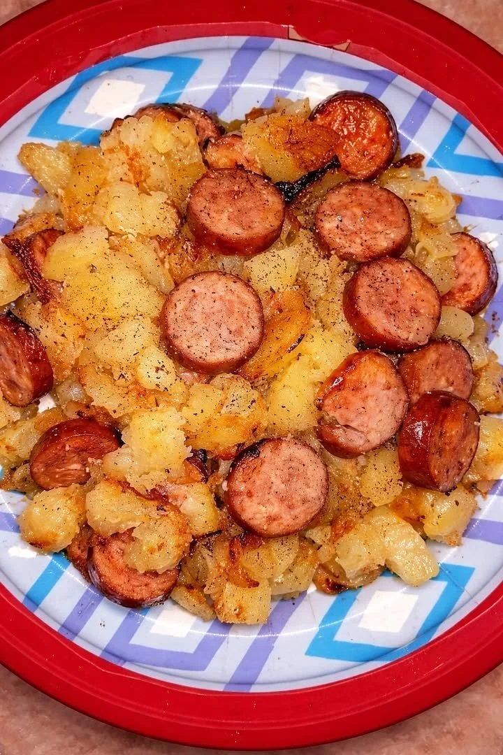 Fried potatoes with onions and smoked Polish sausage served on a plate