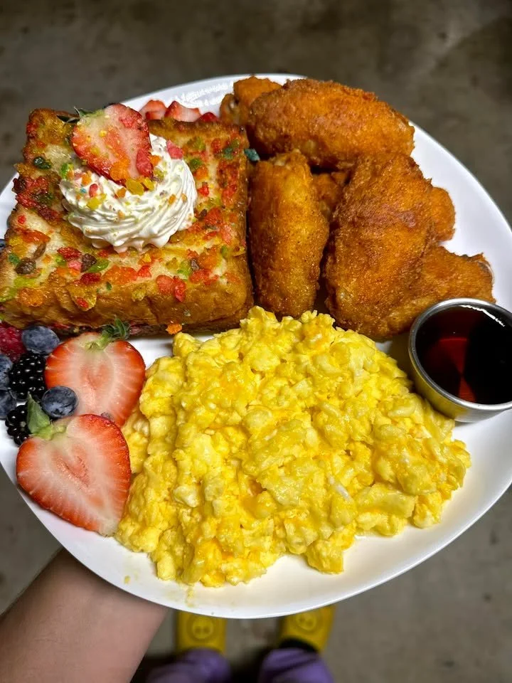 A colorful plate of Fruity Pebbles French Toast topped with syrup and fresh fruit