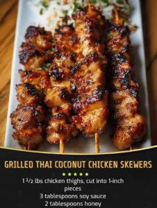 Grilled Thai Coconut Chicken skewers served with dipping sauce and fresh herbs.