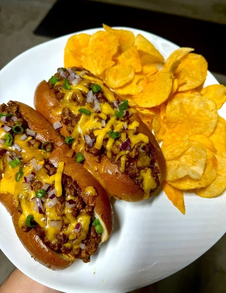 Plate of chili dogs served with Lays and Kool-Aid drink on the side.