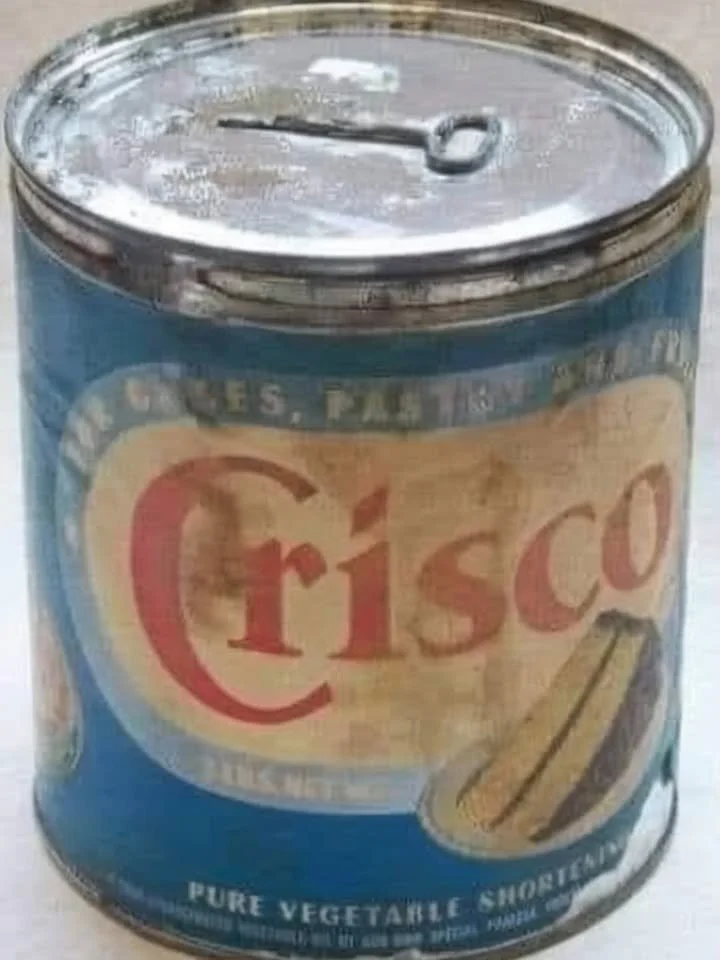 A person skillfully opening a can using a traditional can opener.