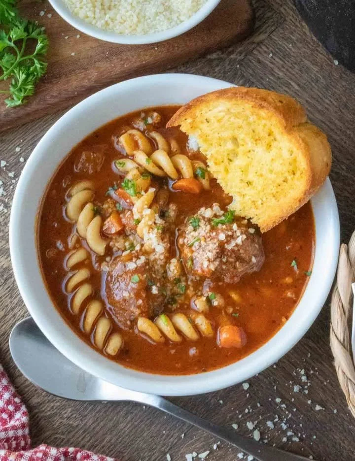 Bowl of Italian meatball soup with fresh herbs and vegetables