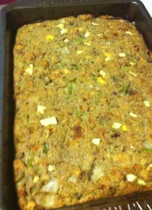 Mama's Cornbread Dressing served on a plate with herbs and vegetables.